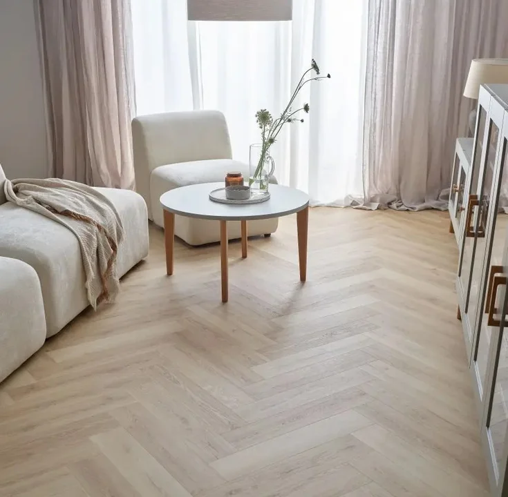 Jasny salon z podłogą w jodełkę i minimalistycznymi meblami.